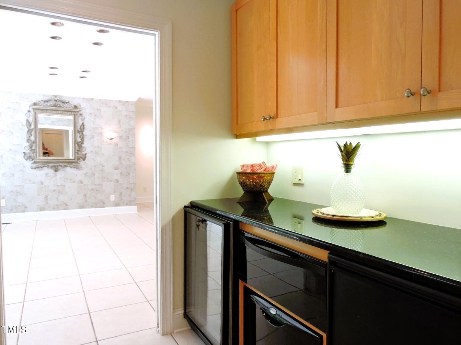 Built-in wet bar with wood cabinets, dark countertop, and under-counter beverage appliances