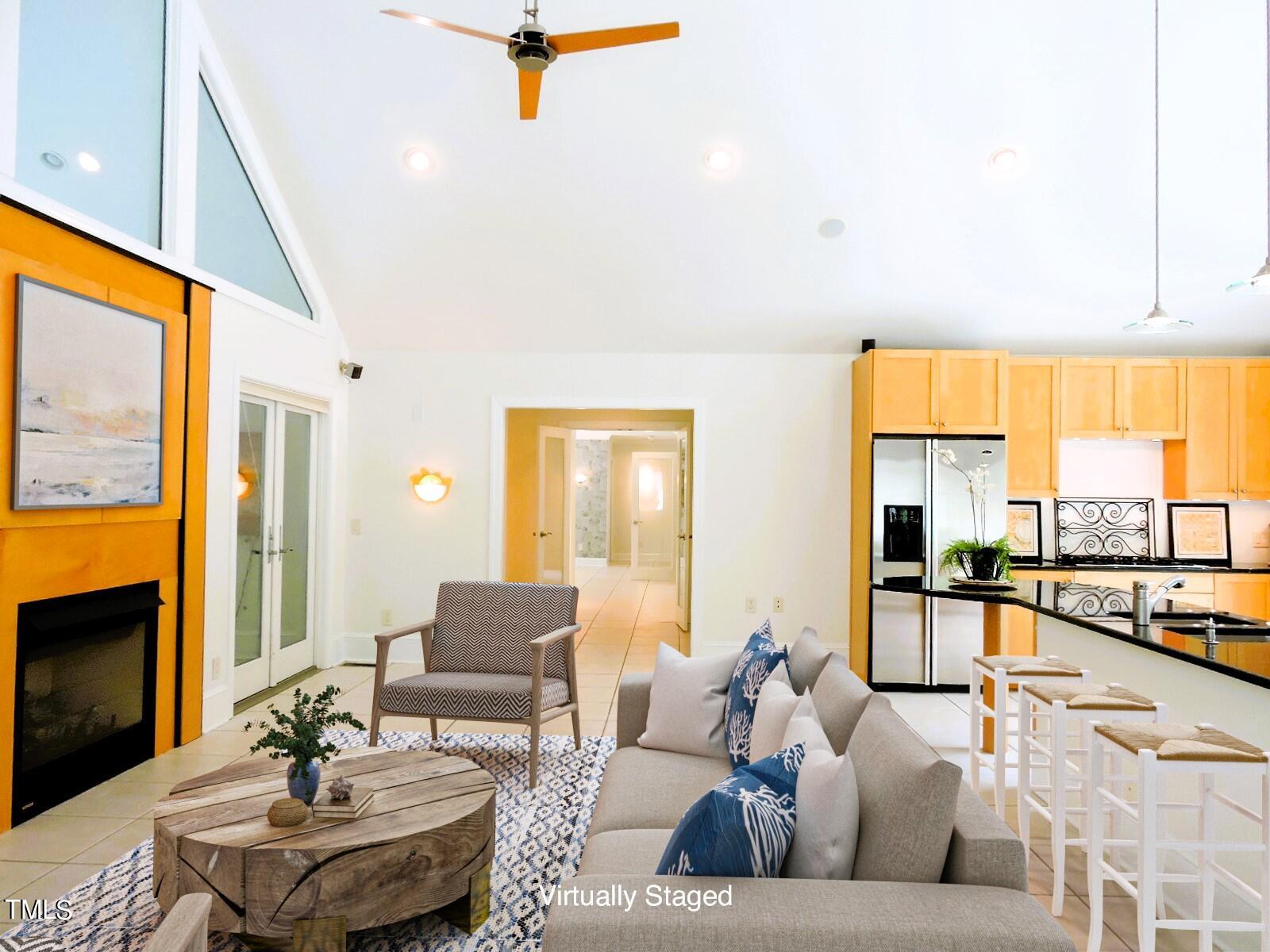 Open-plan living room and kitchen with a vaulted ceiling, fireplace, and light wood cabinetry.