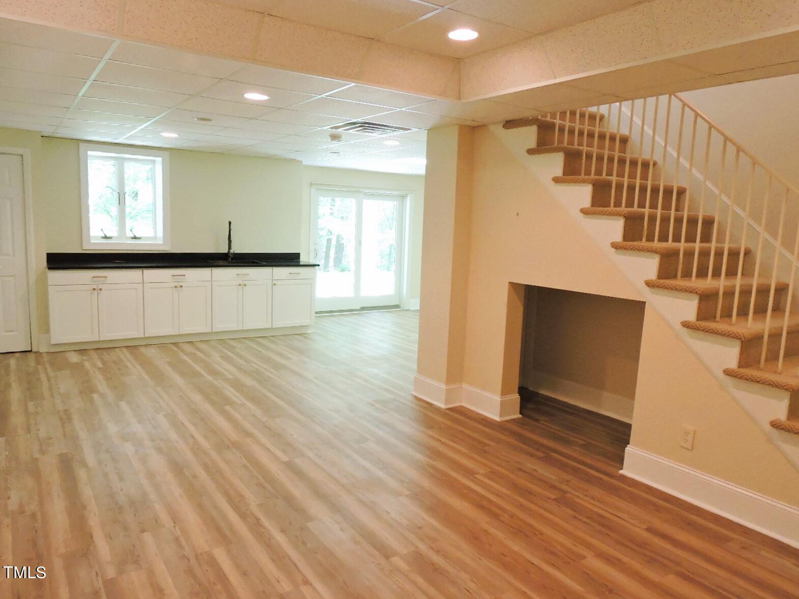 Lower-level living area with a compact kitchenette and carpeted stairs.