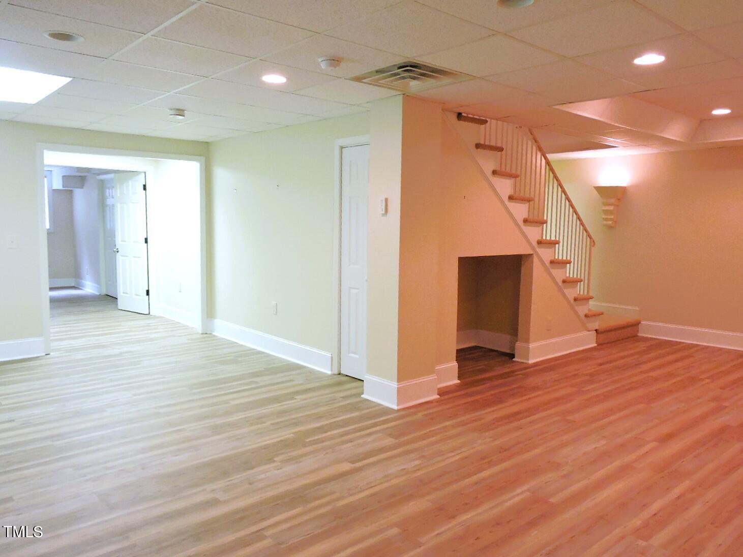 Unfurnished interior with a staircase, open doorway, and wood-look plank flooring.