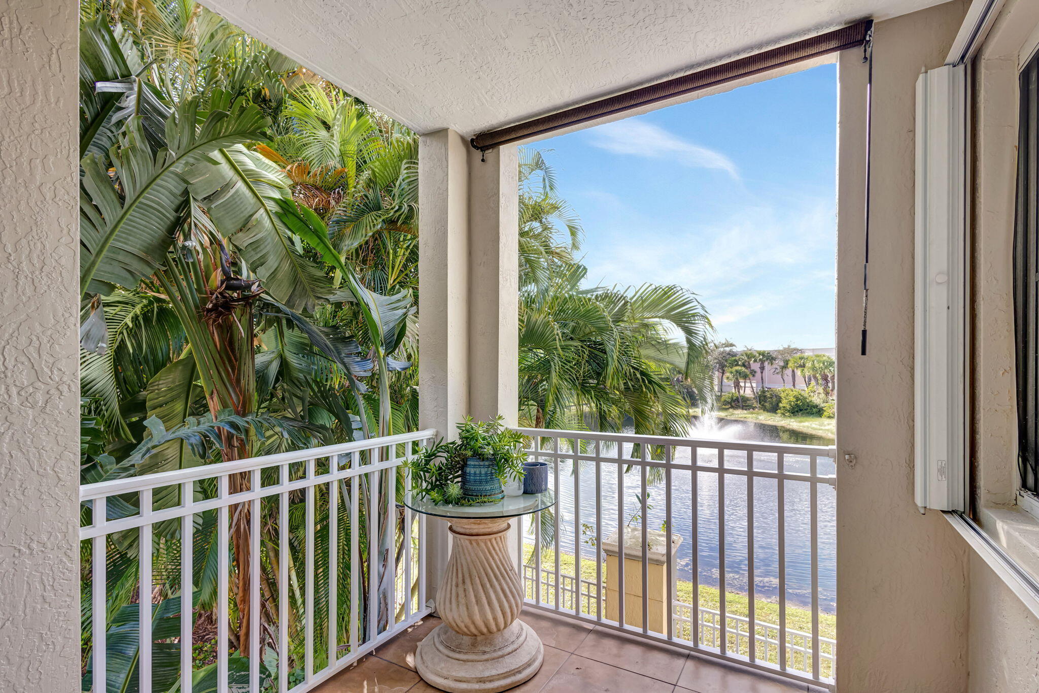 Covered balcony overlooking a waterway, framed by lush tropical palms.
