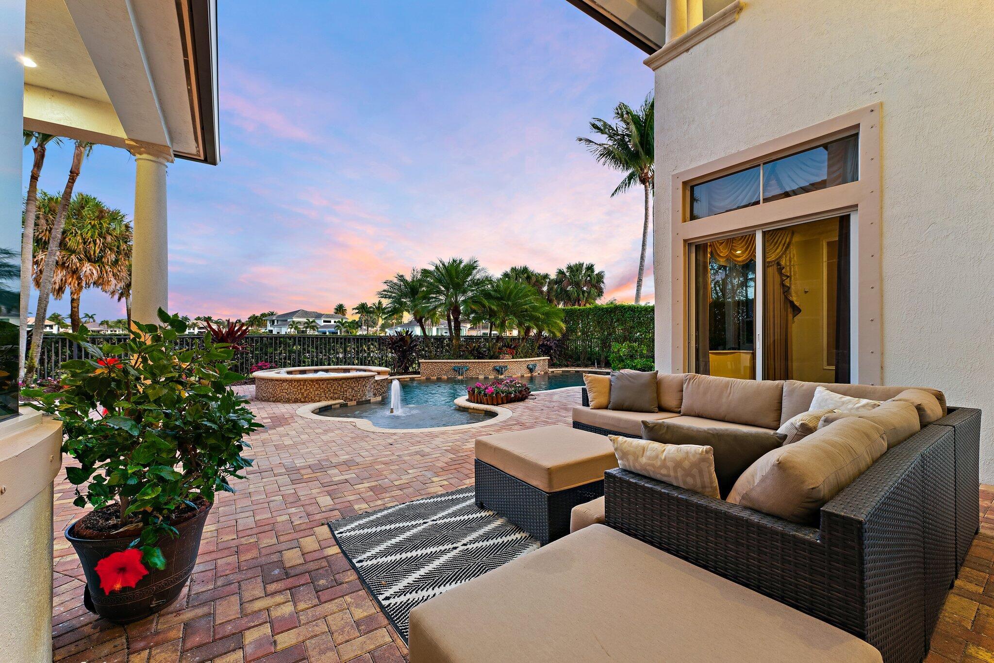 Patio with wicker lounge seating beside a pool and raised spa at dusk.