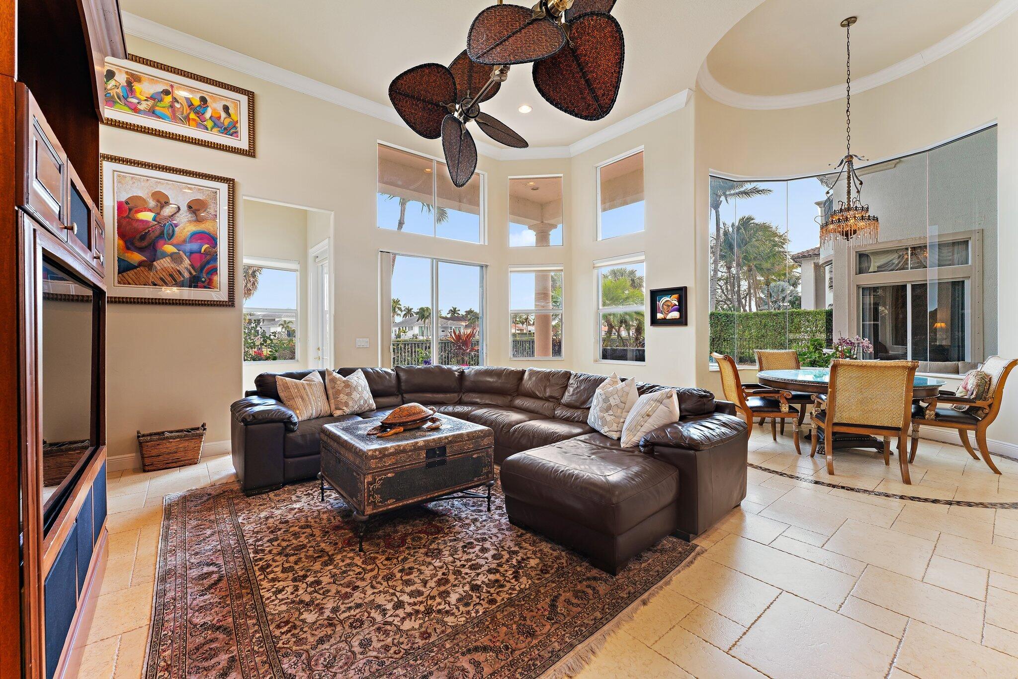 Living room with a leather sectional, patterned rug, and tall windows beside the dining area.