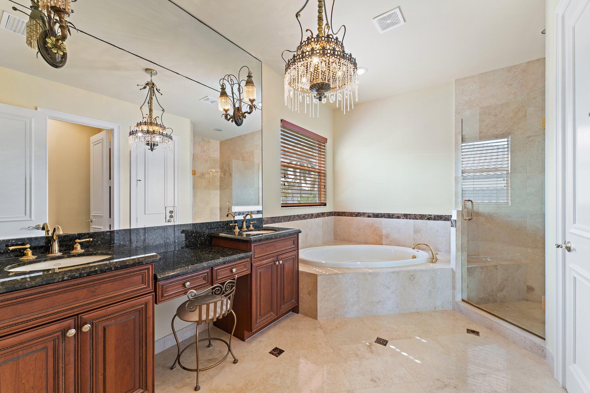 Primary bathroom with a dark wood double vanity, built-in soaking tub, and glass-enclosed shower.