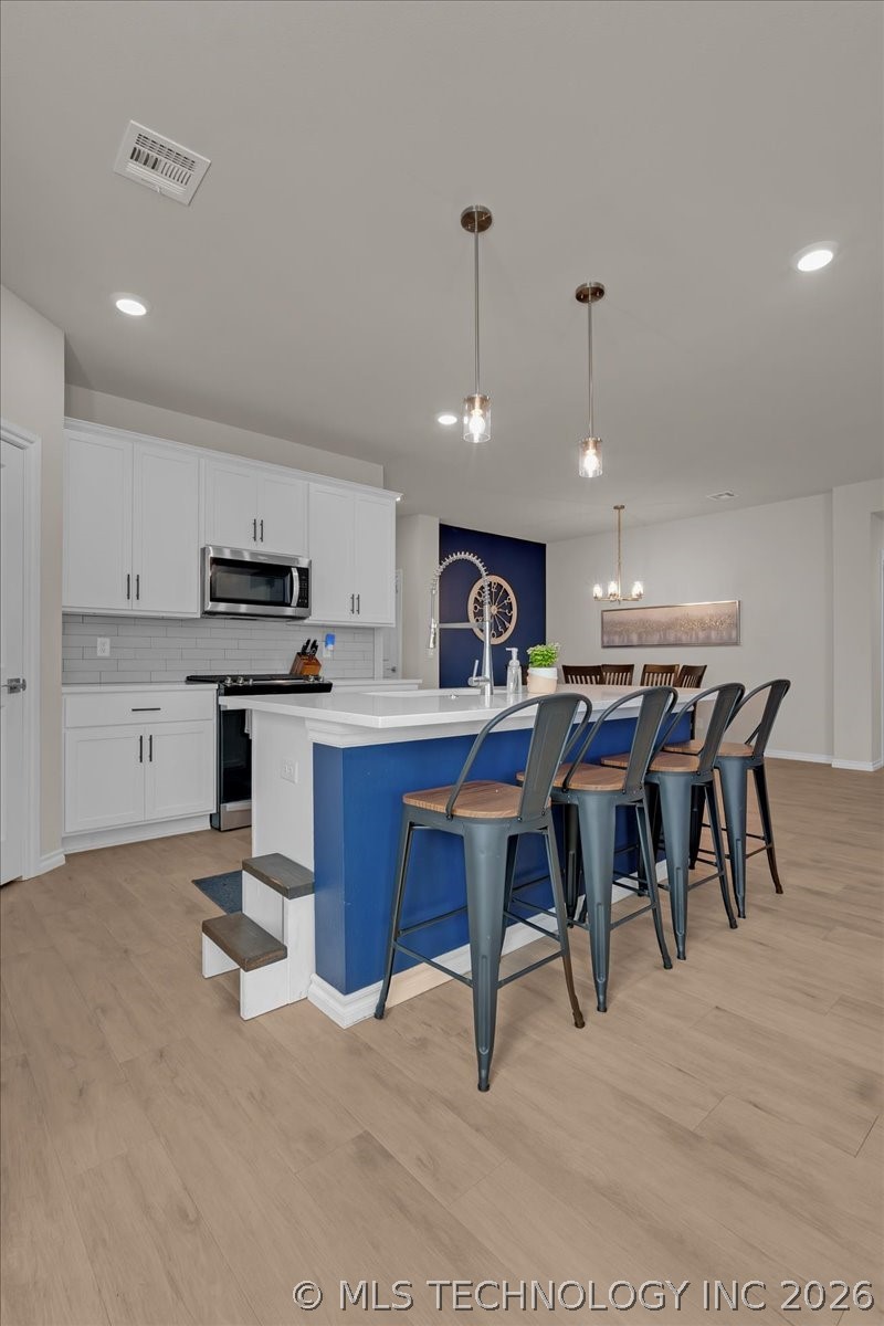 Kitchen with a blue island, bar stools, white cabinets, and an adjoining dining area.