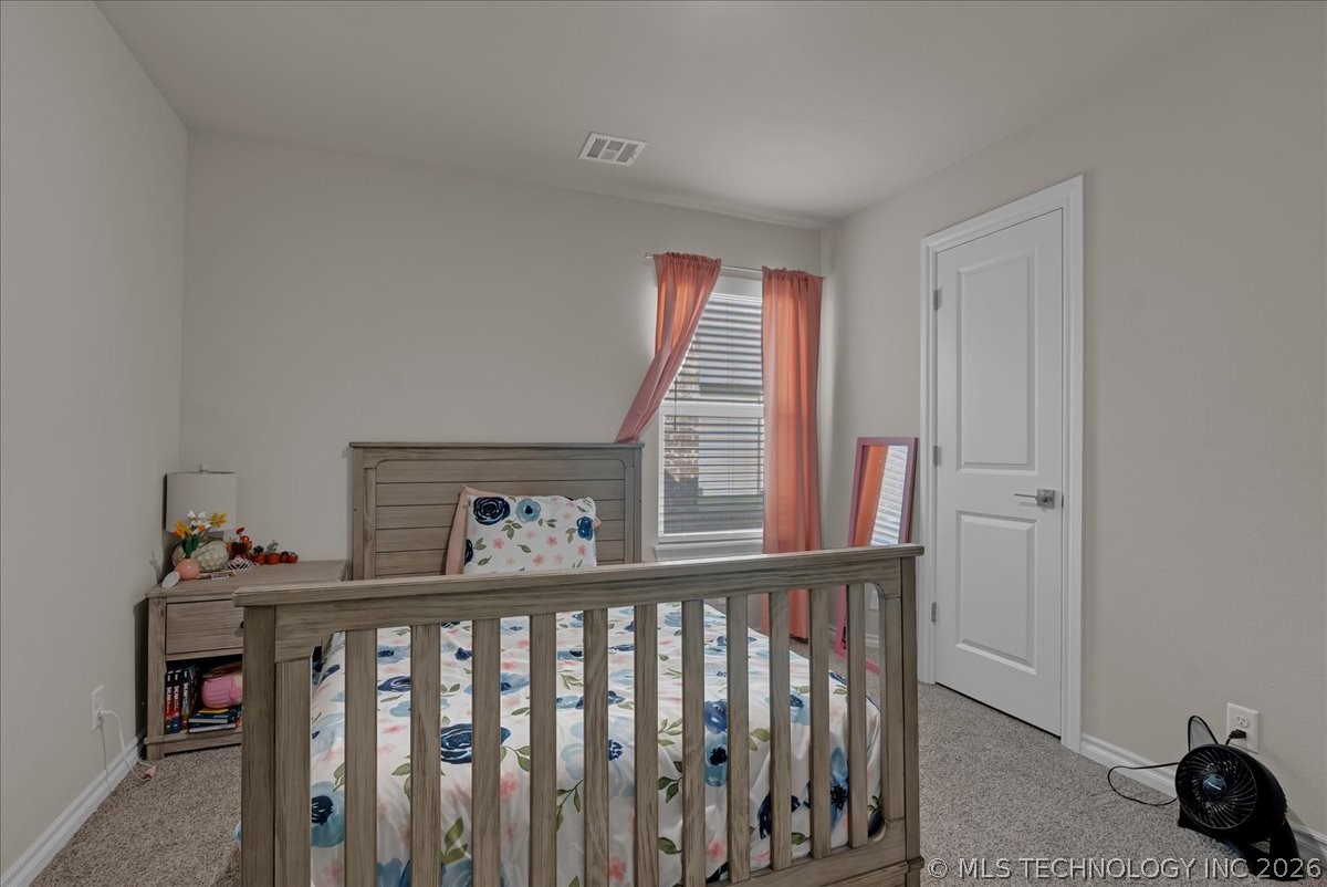 Furnished bedroom with a wooden bed, floral bedding, coral curtains, and beige carpet.