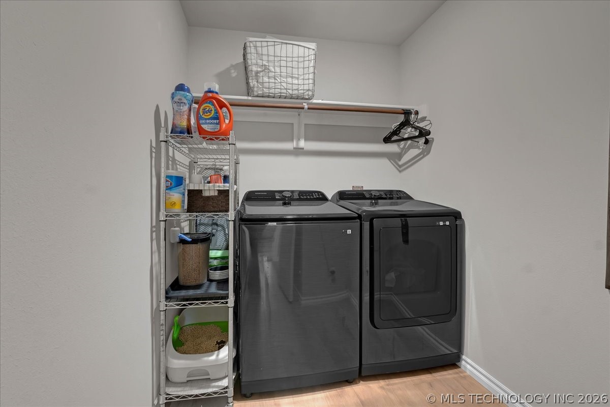 Laundry room with matching dark gray washer and dryer, wire shelving, and a wall-mounted hanging rod.