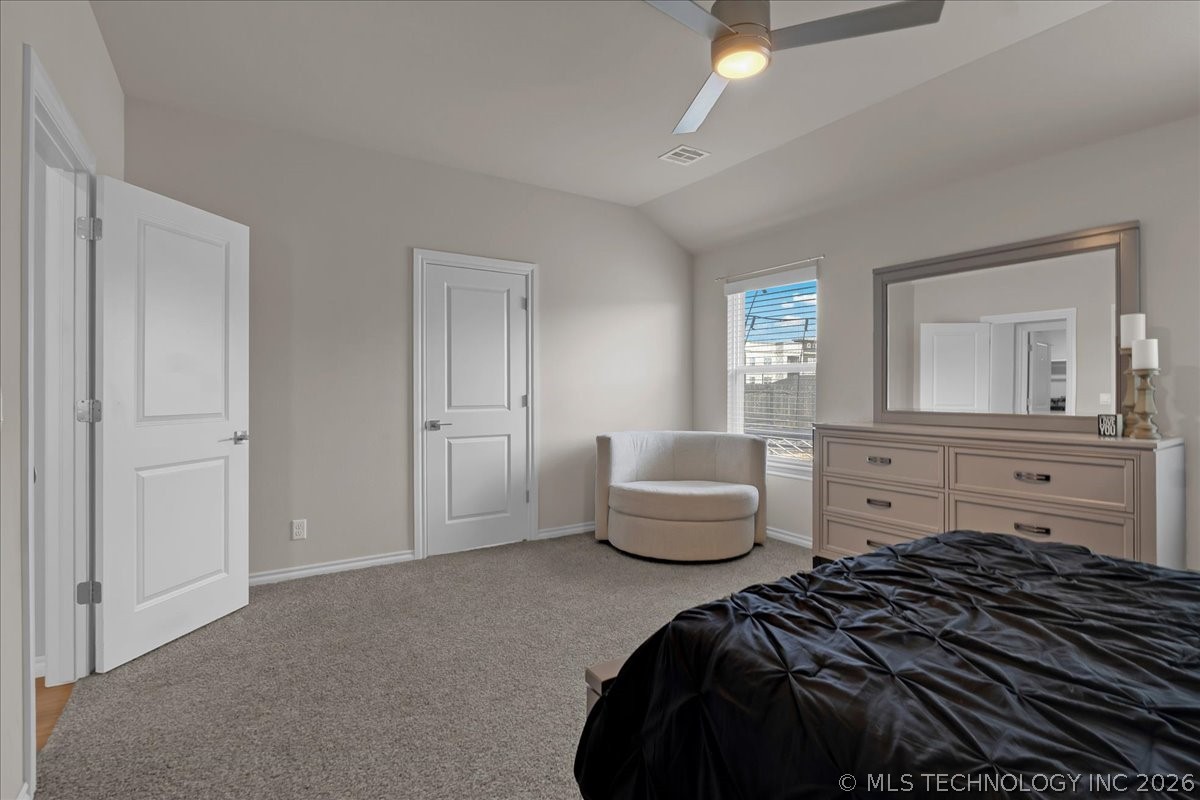 Bedroom with a black-covered bed, gray carpet, and a dresser with a large mirror.