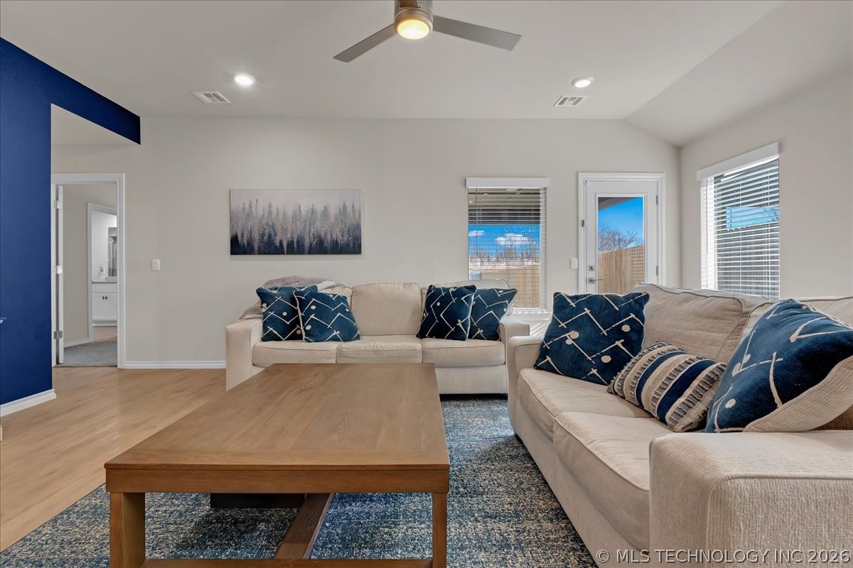 Living room with beige sofas, navy patterned pillows, and a wooden coffee table on a blue rug.