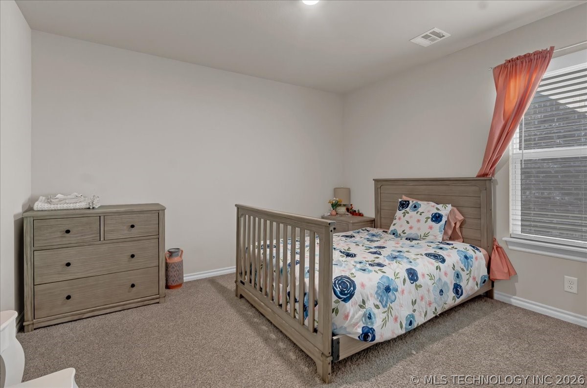Bedroom with floral bedding, a wooden bed and dresser, and coral curtains.