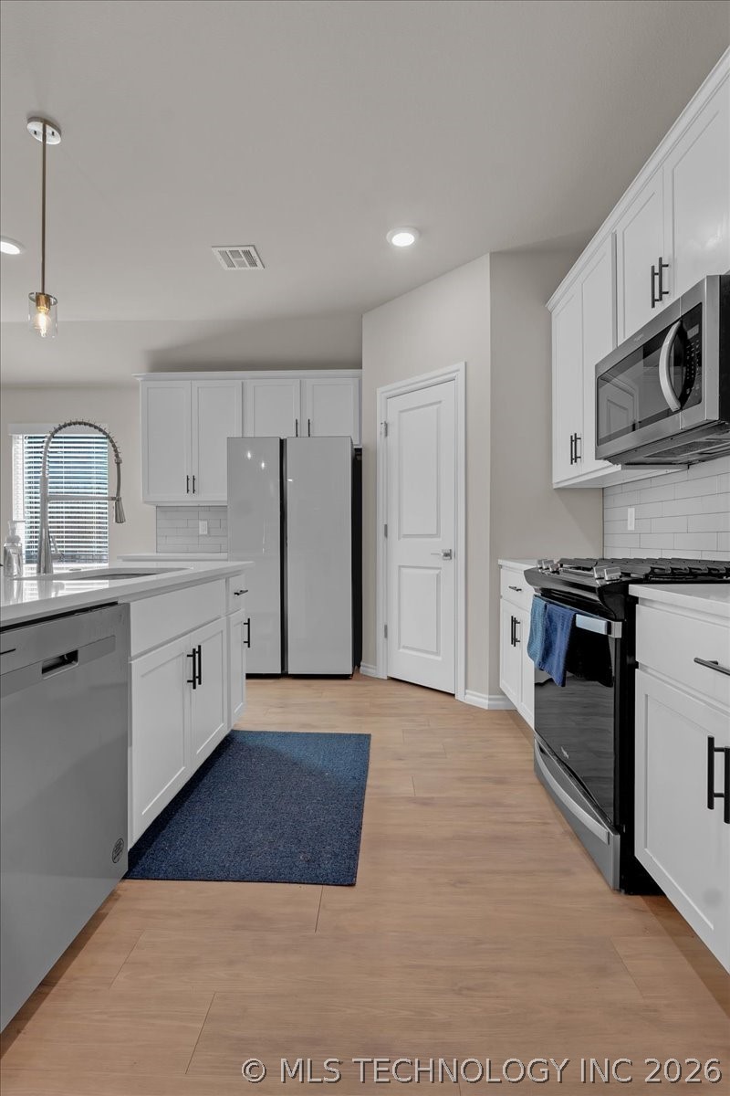 Modern kitchen with white cabinets, stainless appliances, and a large island with a sink.