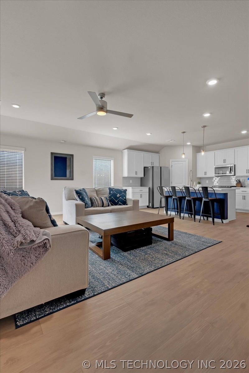 Open-plan living room and kitchen with beige sofas and a dark blue island.