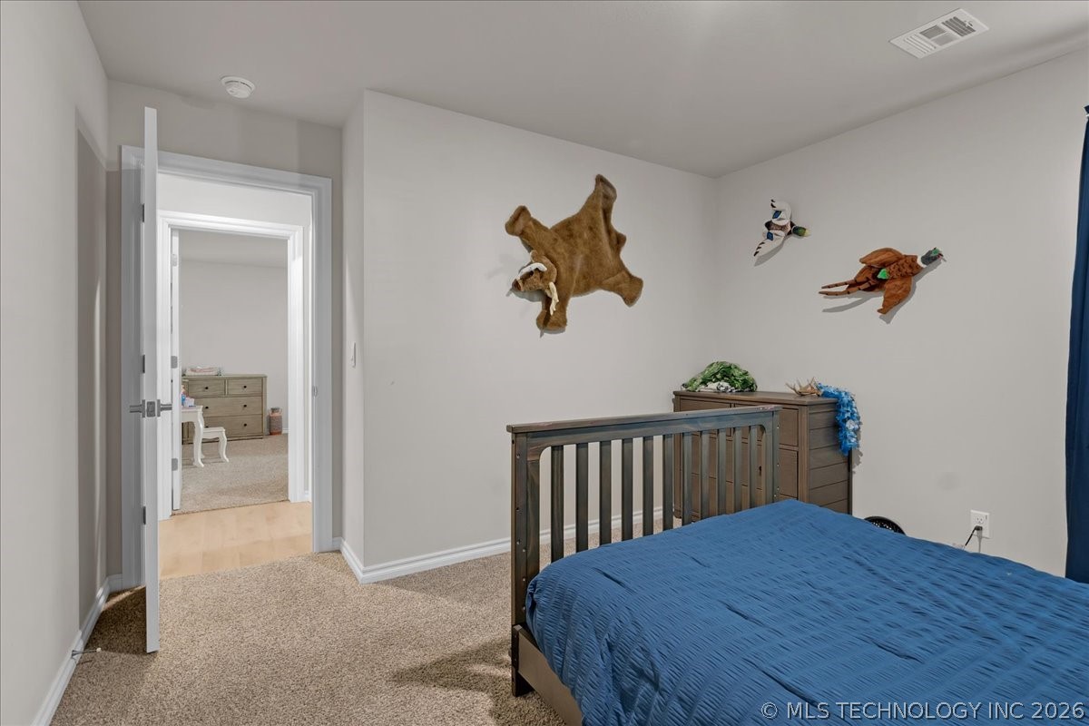 Bedroom with a blue bed, wooden crib-style rail, animal wall decorations, and an open doorway.