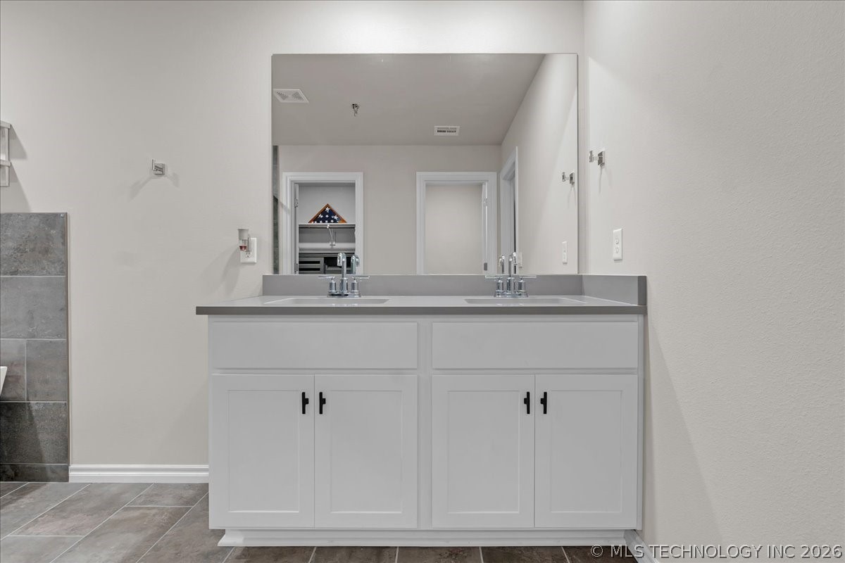 Bathroom with a white double-sink vanity, gray countertop, and large mirror.