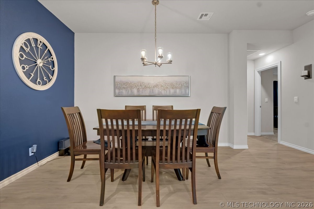 Dining room with a dark wood table and chairs beside a blue accent wall and large clock.