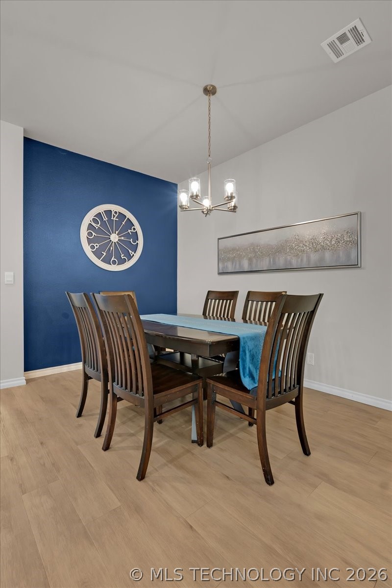 Dining room with a dark wood table, blue accent wall, large clock, and chandelier.