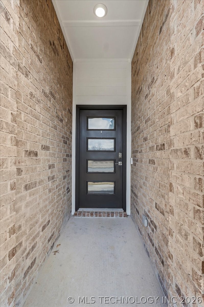 Covered brick entry with a black front door featuring four horizontal glass panels.
