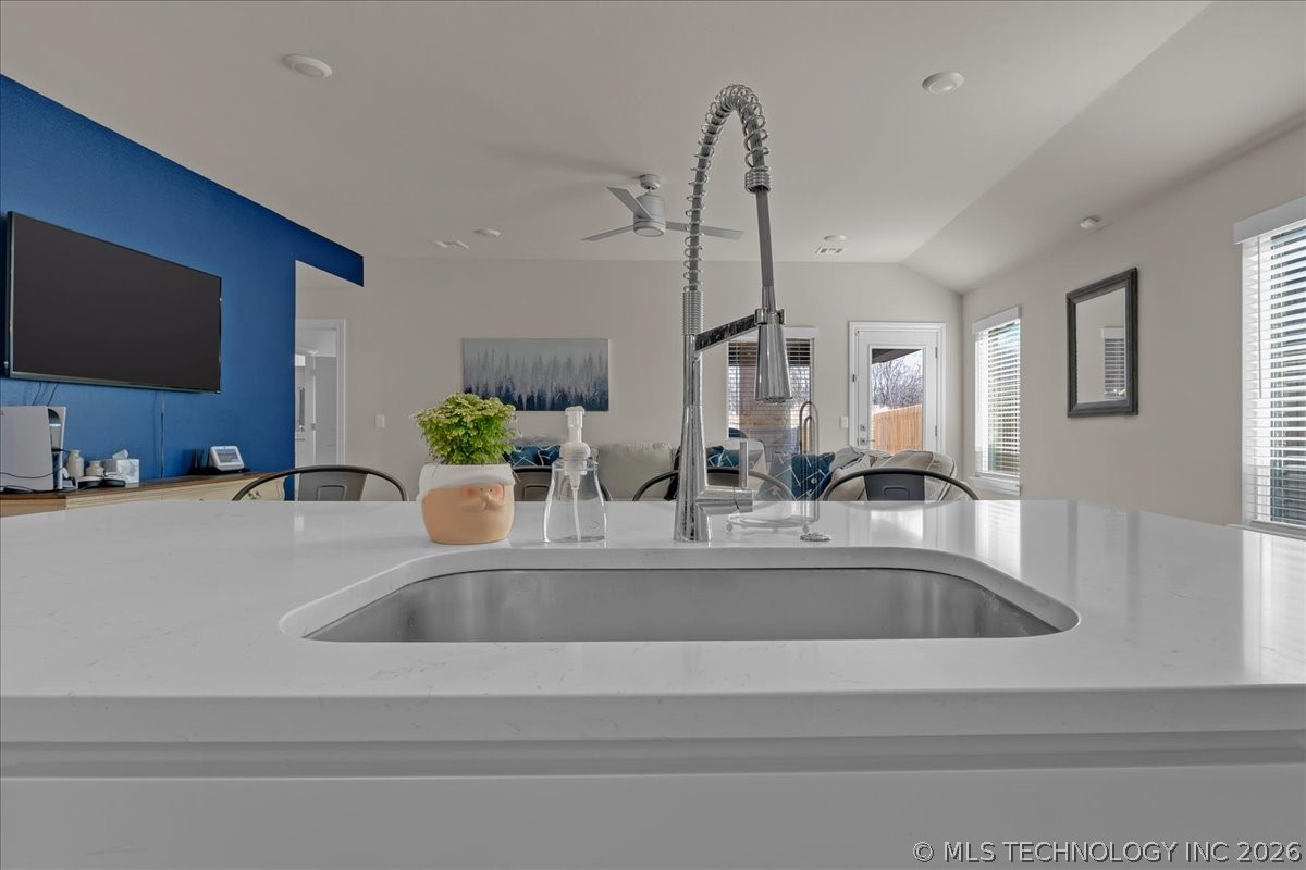 Kitchen with a white quartz island, undermount sink, and tall spring-coil faucet.