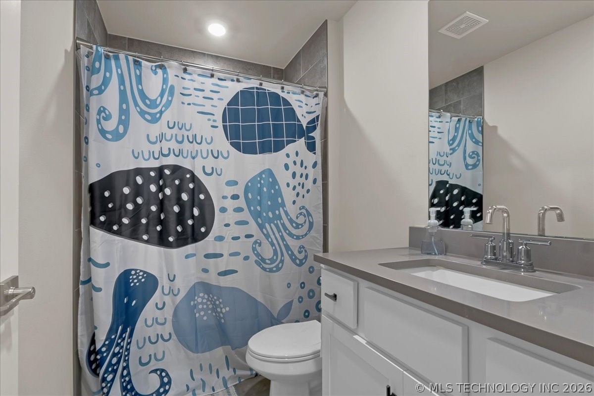 Bathroom with a gray-topped vanity and a blue, black, and white patterned shower curtain.