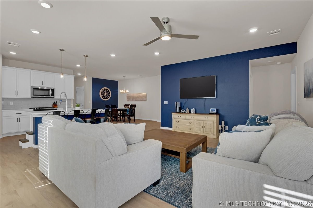 Open-plan living room with pale sofas, a navy television wall, and kitchen and dining areas beyond.
