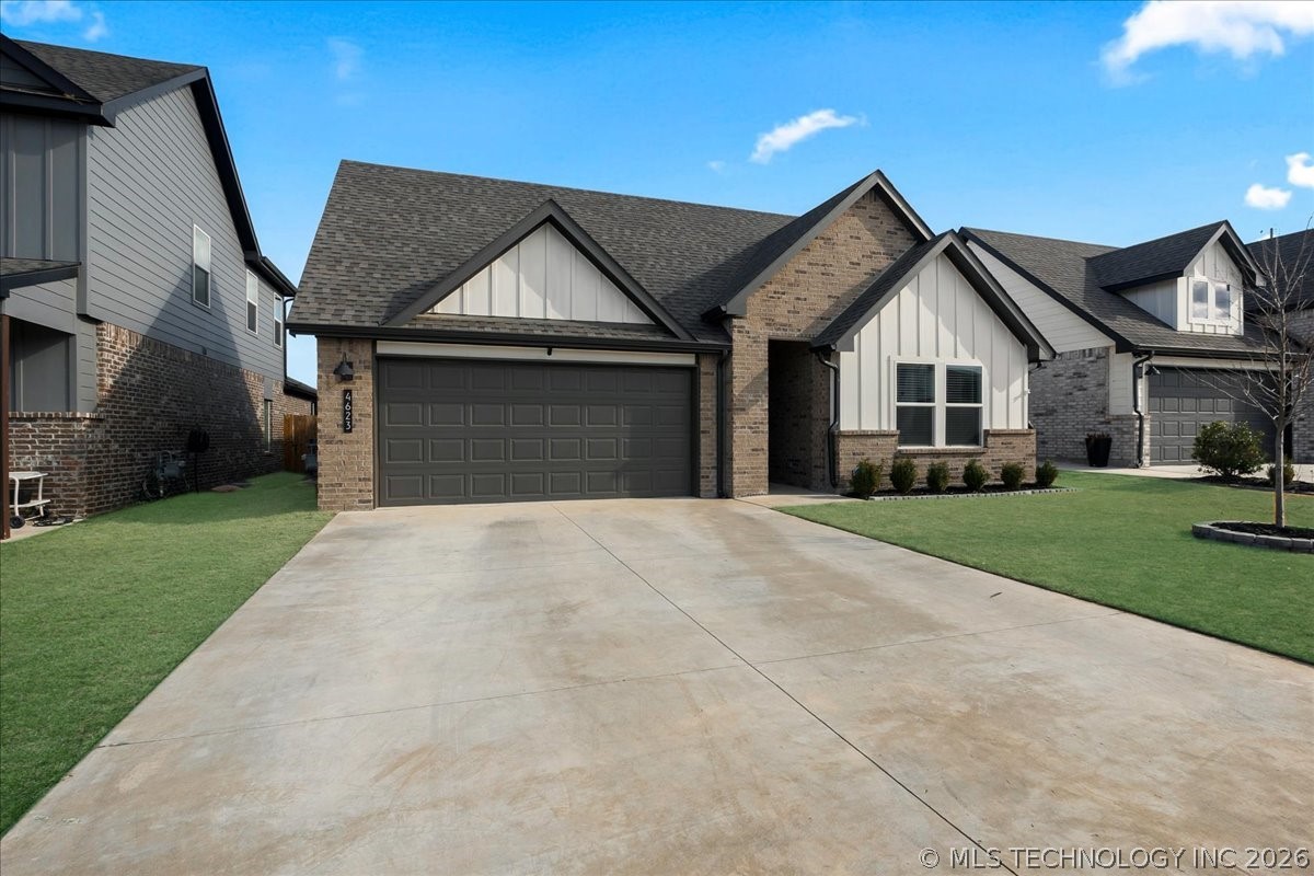 Brick-and-white house with a double garage, peaked gables, and a wide concrete driveway.