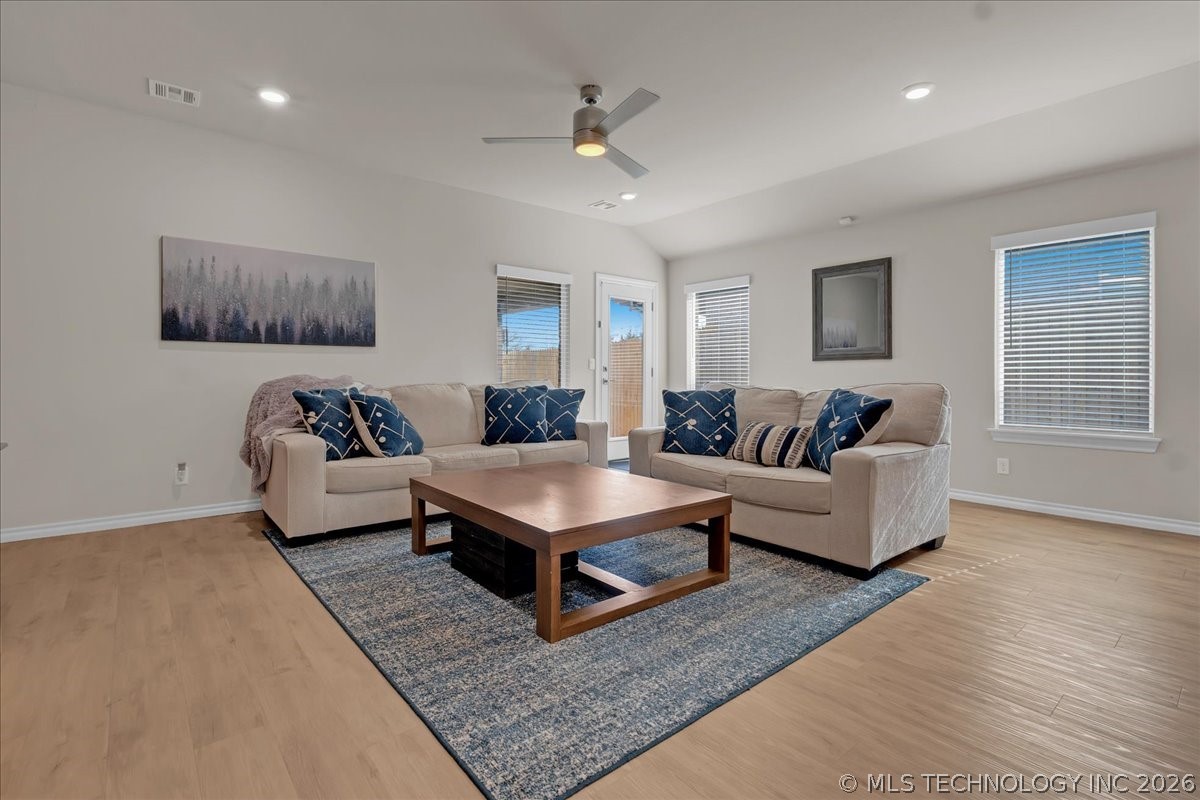 Furnished living room with beige sofas, blue pillows, a wood coffee table, and a ceiling fan.