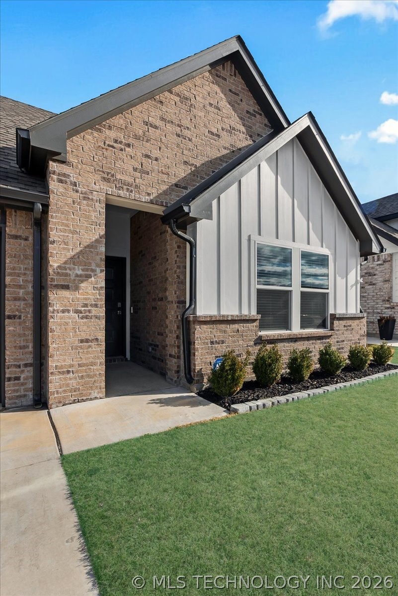 Home entry with tan brick, a white gable, paired windows, and a recessed front door.