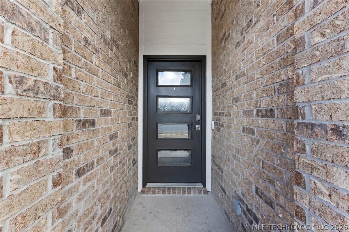 Recessed brick entry with a black front door featuring four horizontal glass panels.