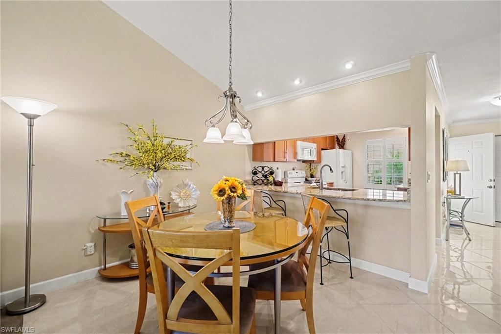 Dining area with a round glass-top table and wooden chairs beside the open kitchen.