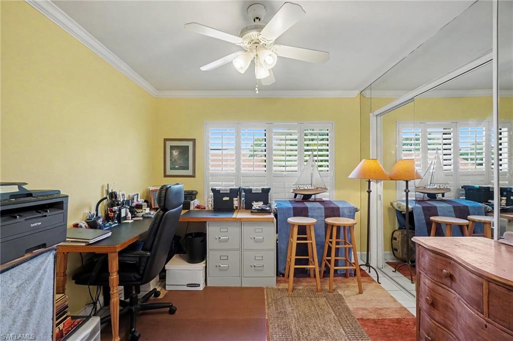 Furnished home office with yellow walls, mirrored closet doors, and shuttered windows.