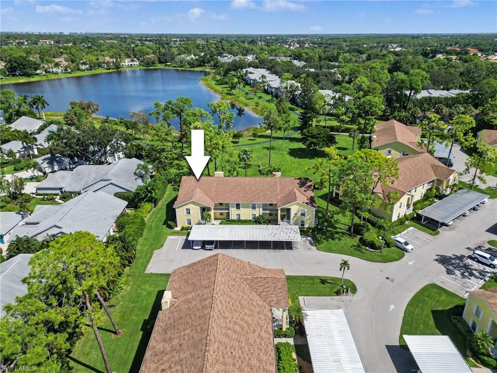 Aerial view of a condominium building beside a lake, marked with a white arrow.