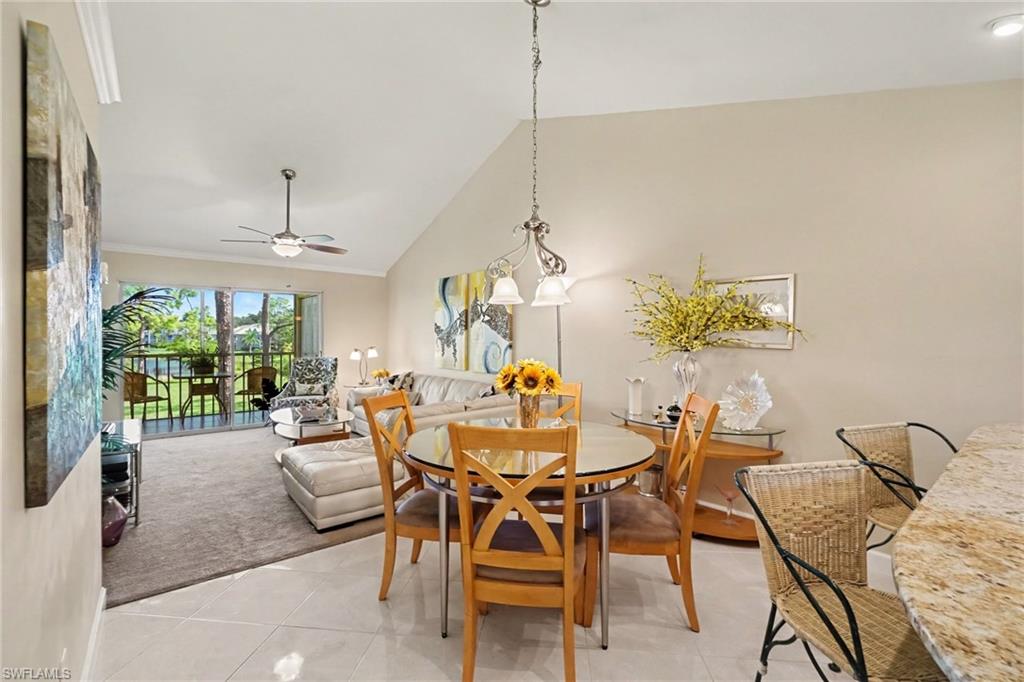 Open living and dining area with a glass-top table, cream sectional, and patio doors overlooking water.