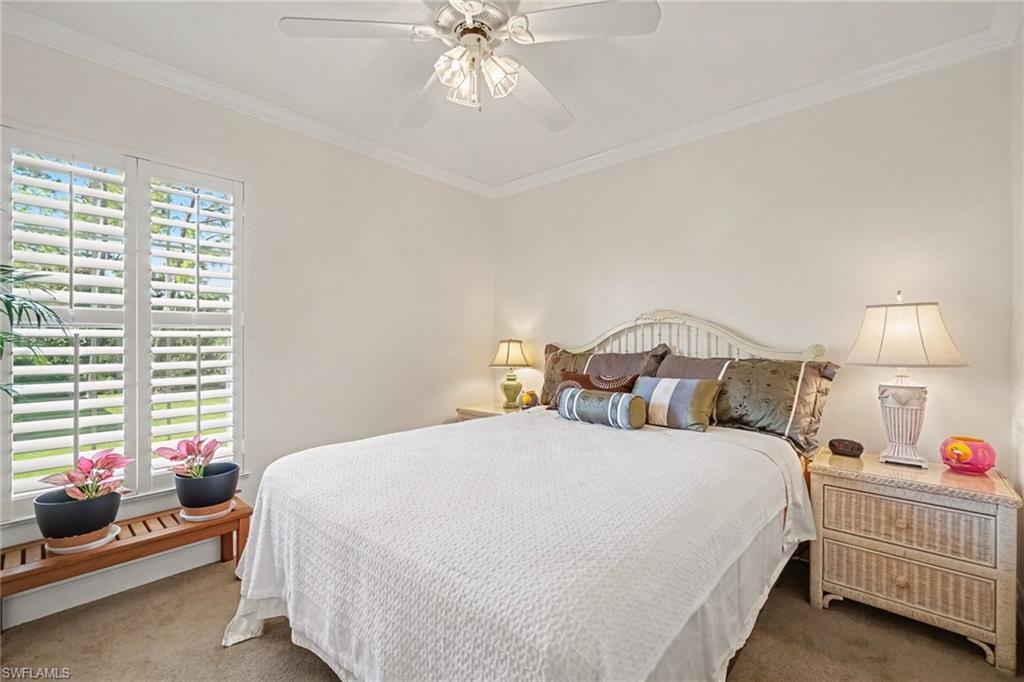 Bedroom with a large bed, plantation shutters, and a ceiling fan.