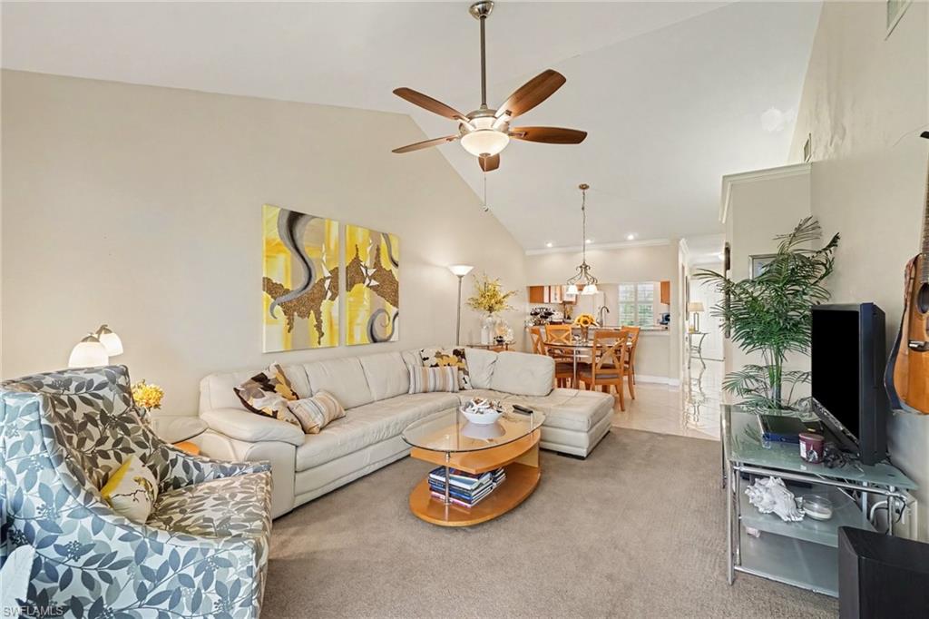 Furnished living room with a cream sectional, patterned chair, and dining area beyond.