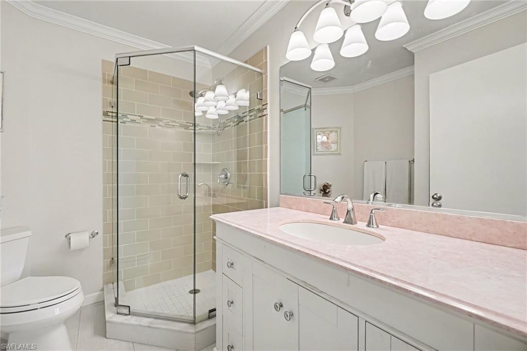 Bathroom with a glass corner shower and a long pink countertop vanity.