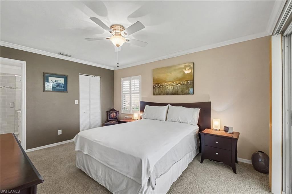 Bedroom with a white bed, dark wood nightstands, ceiling fan, and sliding glass door.