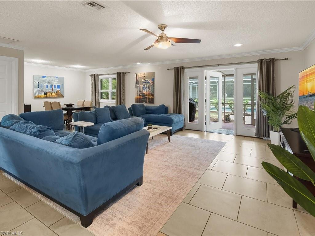 Living room with a blue sectional, tiled floors, and glass doors opening toward the pool.