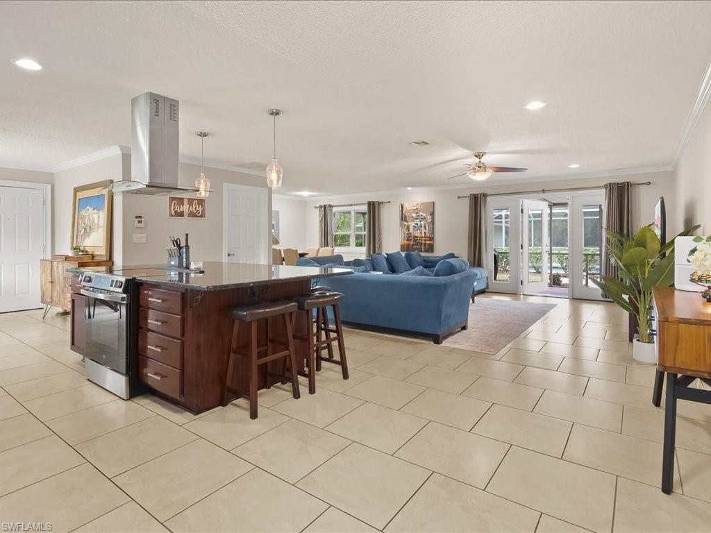 Open-plan kitchen and living room with a dark wood island, blue sectional, and glass doors to the patio.