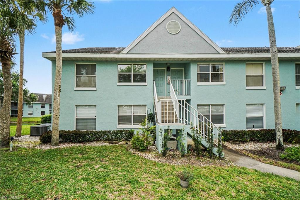 Aqua two-story condominium exterior with a central white staircase and palm trees.