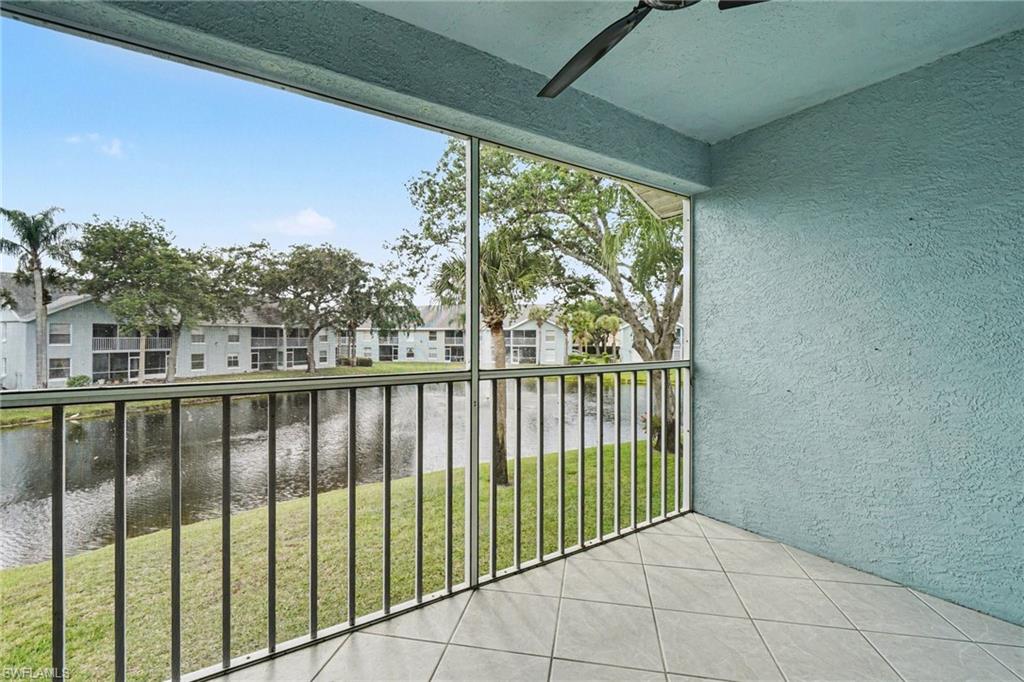 Covered condo balcony overlooking a canal, with tiled flooring and pale blue stucco walls.