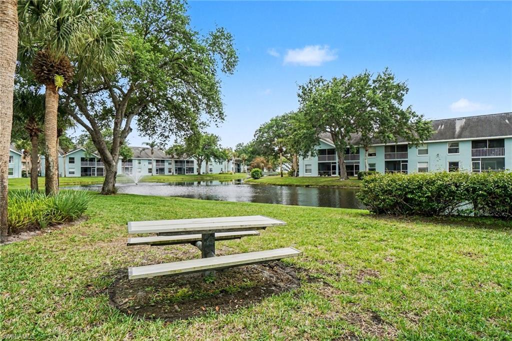 Condominium courtyard with a pond and fountain, mature trees, and a picnic table.