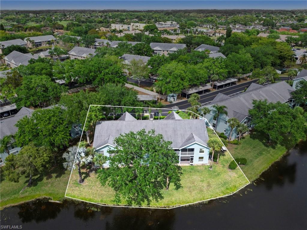 Aerial view of a condominium building on a canal, with its lot outlined in white.