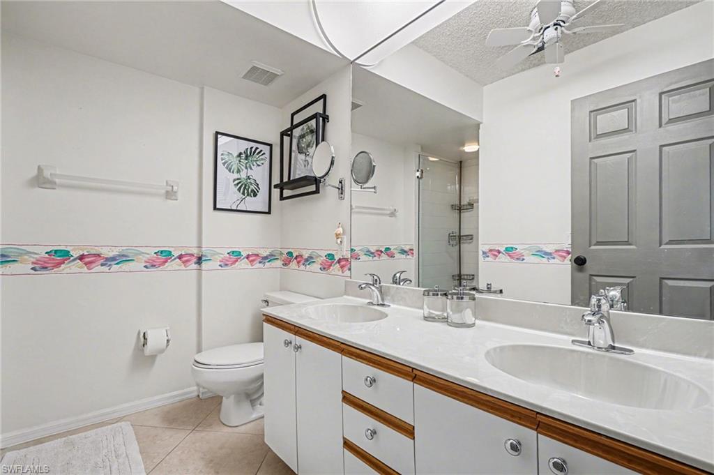 Bathroom with a double-sink vanity, glass shower, and colorful floral wall border.