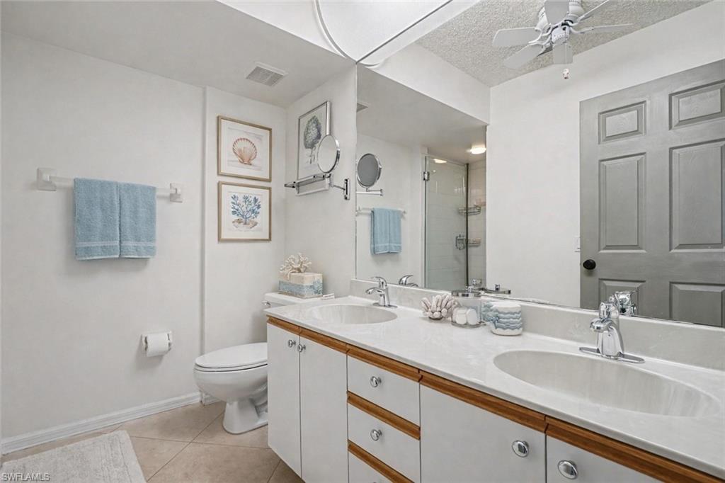 Bathroom with a double-sink vanity, large mirror, glass shower, and coastal accents.