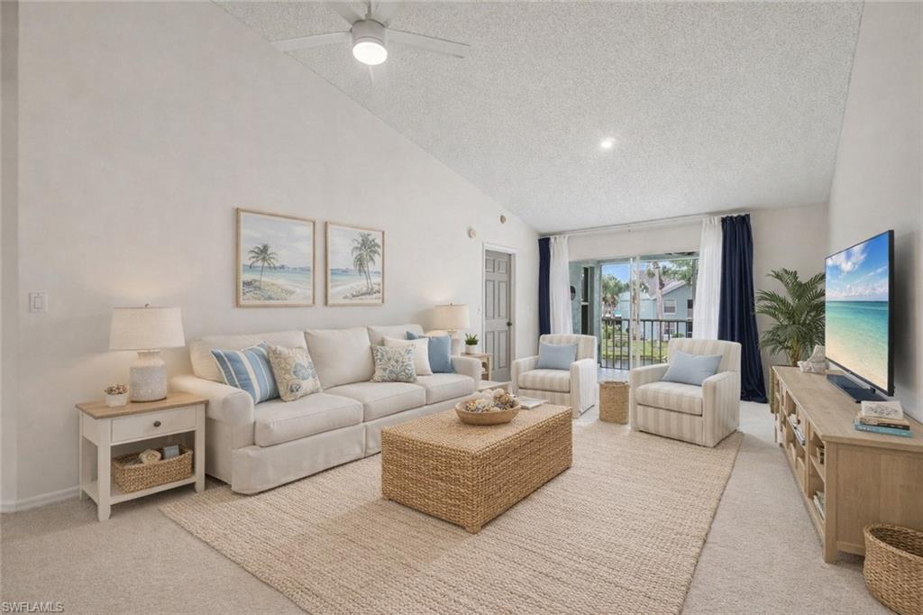 Living room with a white sofa, woven coffee table, and sliding doors to a balcony.