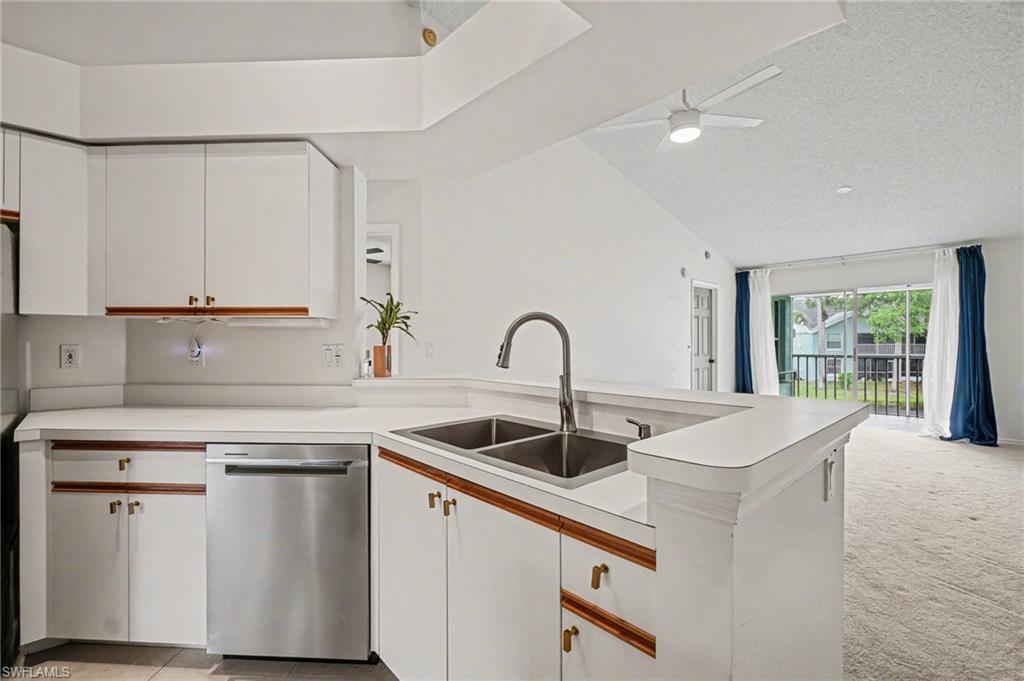 Kitchen with white cabinetry, a peninsula sink, and sliding doors opening to an unfurnished living area.