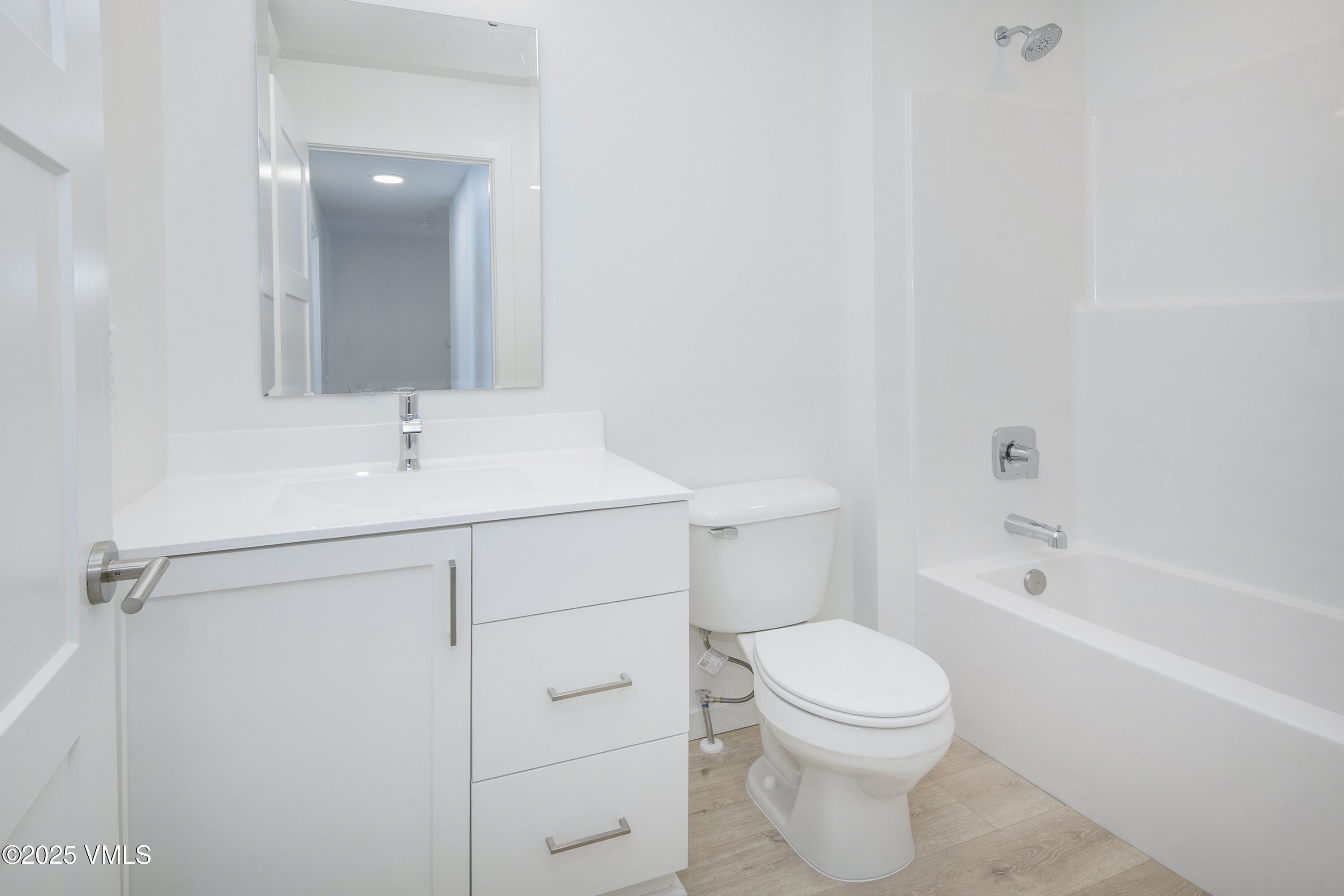 Bright white bathroom with a modern vanity, toilet, and bathtub with shower.