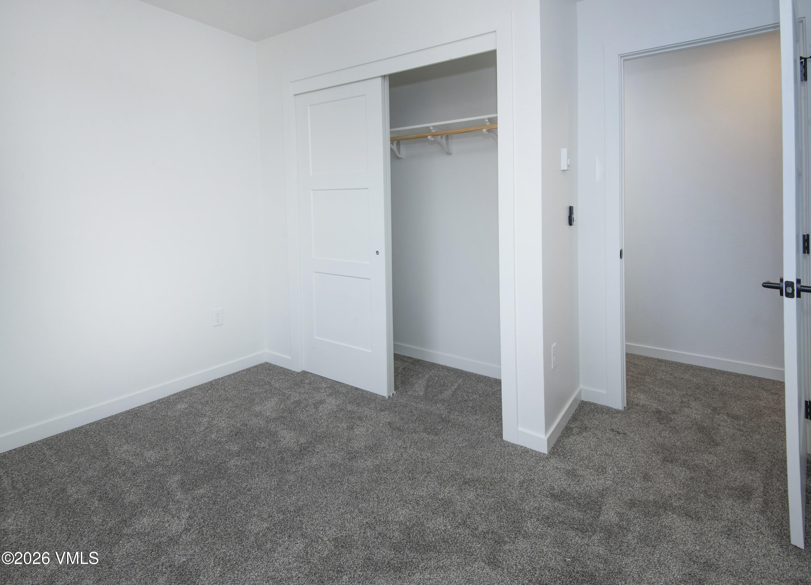 Unfurnished bedroom with gray carpet and an open sliding closet.