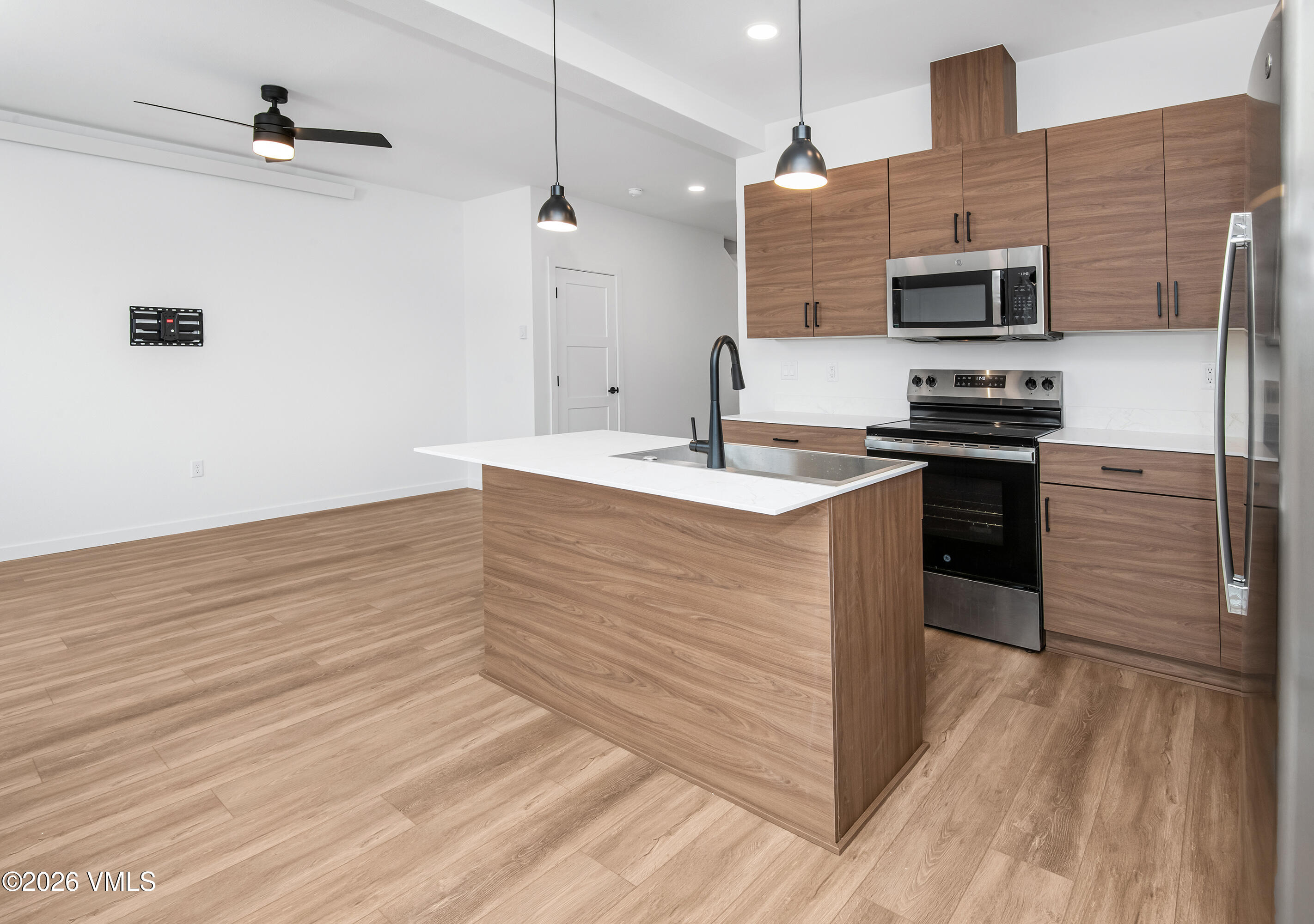 Modern kitchen with a wood-front island, white countertop, and stainless-steel appliances.