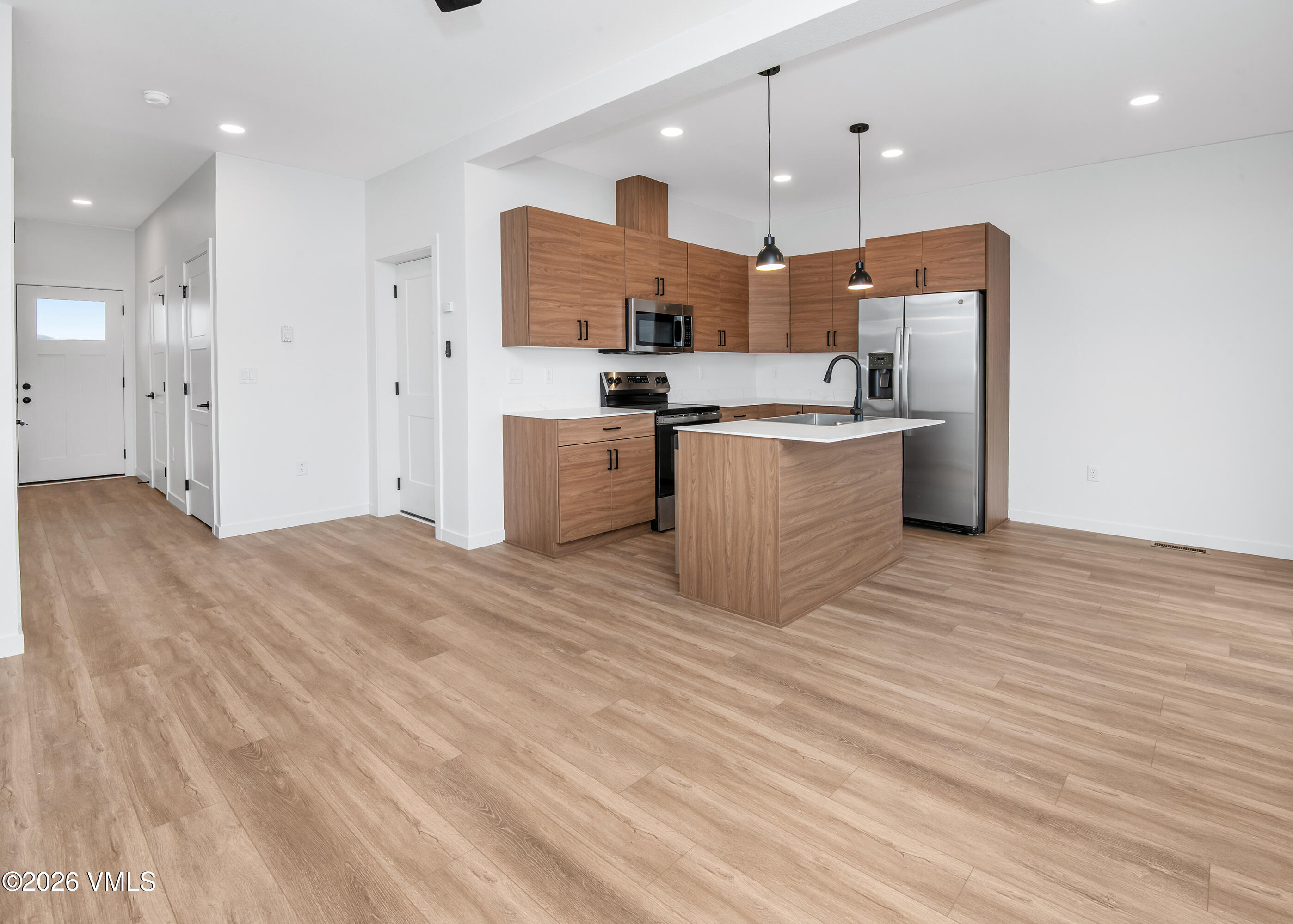 Kitchen with warm wood cabinetry, a white-topped island, and stainless steel appliances.